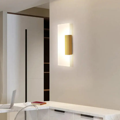 Gold acrylic wall sconce by Decorbites on white wall with warm glow on Tampa Home & Garden Store