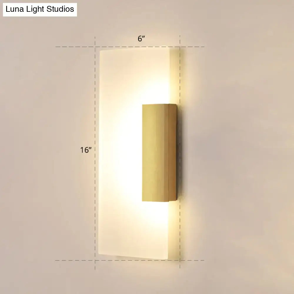 Gold acrylic wall sconce with vertical brass cylinder on a frosted backplate, warm glow on Tampa Home & Garden Store