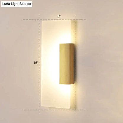 Gold acrylic wall sconce with vertical brass cylinder on a frosted backplate, warm glow on Tampa Home & Garden Store