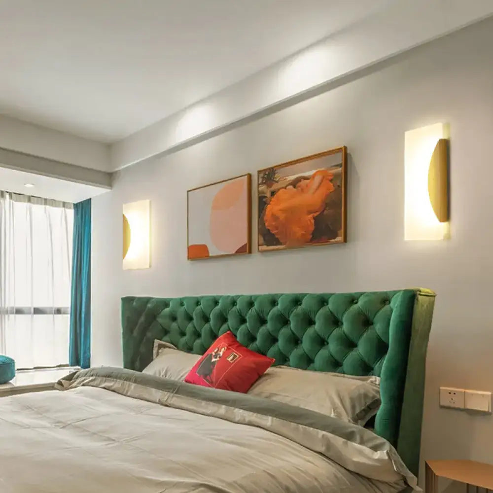 Gold acrylic wall sconces pair with white backplates casting warm light in a modern bedroom on Tampa Home & Garden Store