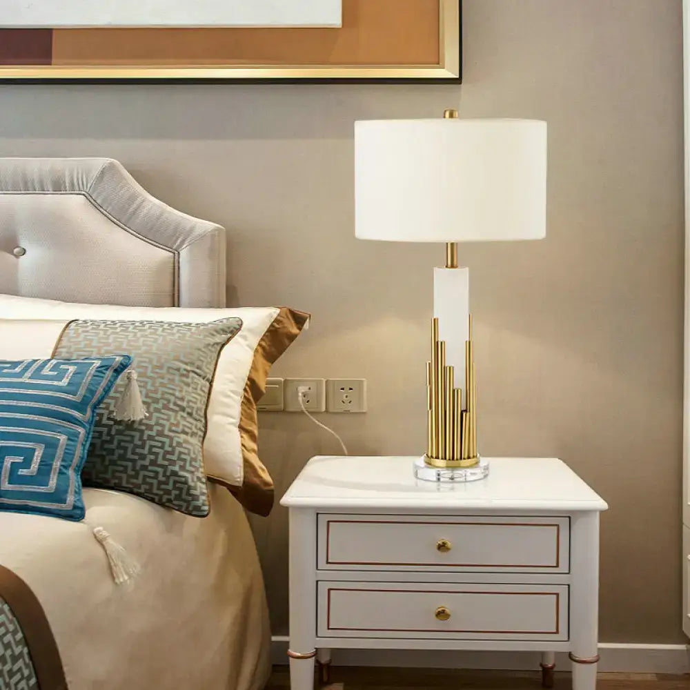 Gold Fabric Drum Table Lamp with white shade and gold-tone sculptural base on nightstand on Tampa Home & Garden Store