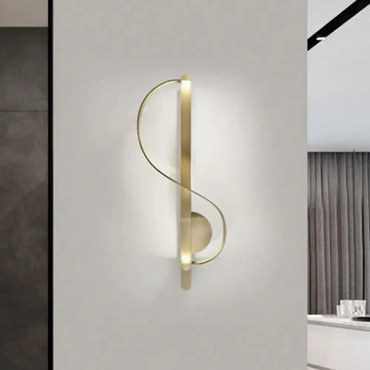 Gold metal s-shaped wall light fixture mounted on neutral wall modern living room corner on Tampa Home & Garden Store