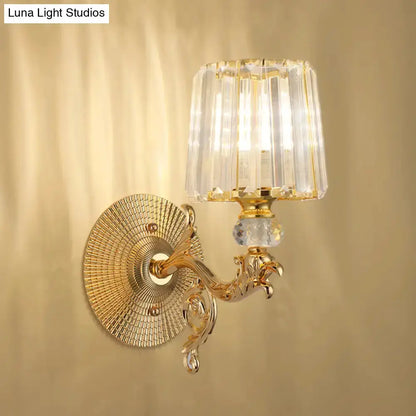 Modern gold wall sconce with crystal tapered shade, ornate arm, round backplate on Tampa Home & Garden Store