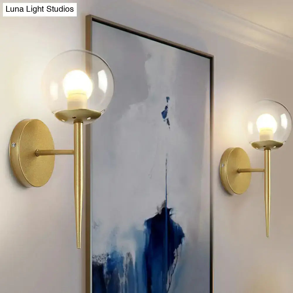Gold Glass Torch Sconce pair with clear glass globes and brass arms beside artwork on Tampa Home & Garden Store
