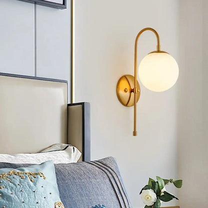 Gooseneck wall sconce in gold by Decorbites with curved arm and white glass globe on Tampa Home & Garden Store