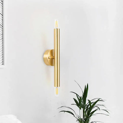 Gold tubular wall sconce with vertical cylindrical bar and round wall mount, LED accents at ends on Tampa Home & Garden Store