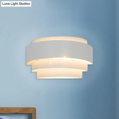 White tiered wall sconce with layered circular bands and warm glow on blue wall on Tampa Home & Garden Store
