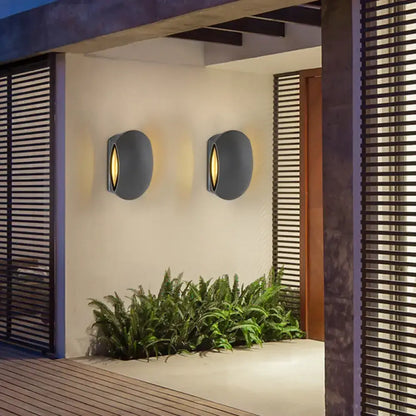 Black oval outdoor sconces, 2 wall-mounted on white wall with warm light on Tampa Home & Garden Store