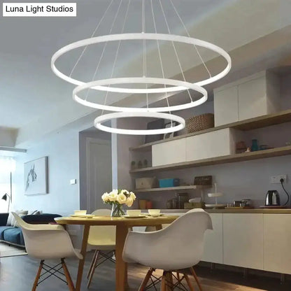 Pendant light with modern interlocking white LED rings over a dining table by Decorbites on Tampa Home & Garden Store