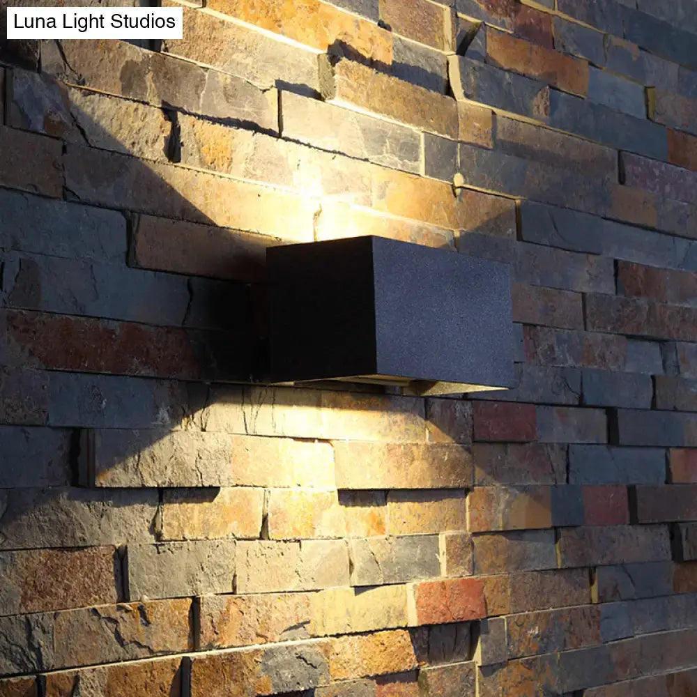 Black rectangle wall sconce by Decorbites, metal fixture casting warm light on a stone wall on Tampa Home & Garden Store
