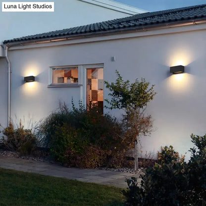 Black rectangle Decorbites outdoor wall sconces (2) on white wall emitting warm light on Tampa Home & Garden Store