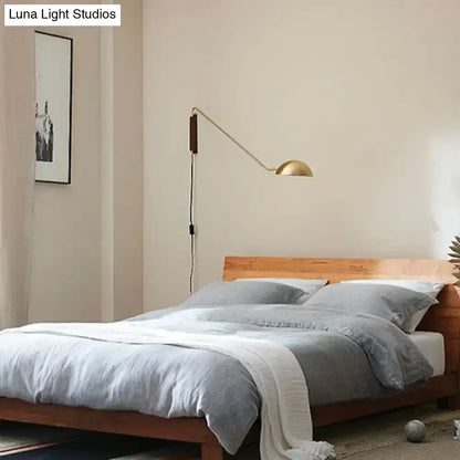 Modern matte black swing-arm bedside wall lamp with wood mount and gold dome shade on Tampa Home & Garden Store
