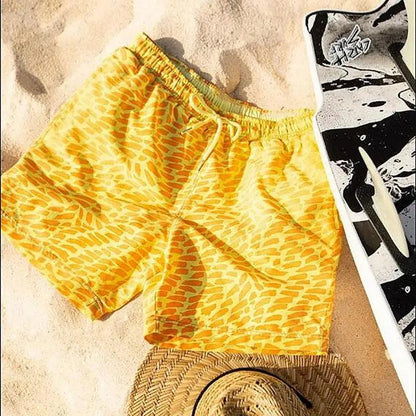 Men's yellow abstract-pattern boardshorts with drawstring waist on sandy beach scene on Tampa Home & Garden Store