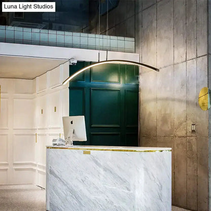 Pendant light curved metallic arc LED fixture over marble reception desk in a modern lobby on Tampa Home & Garden Store