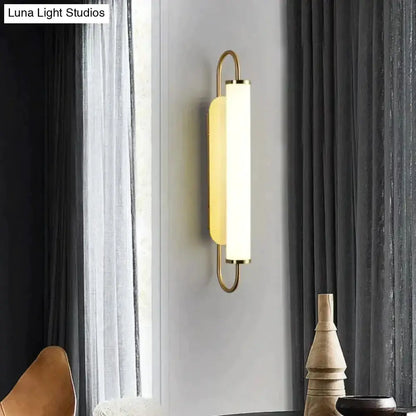 Wall lamp Decorbites gold LED cylindrical sconce with curved brass frame on gray wall on Tampa Home & Garden Store