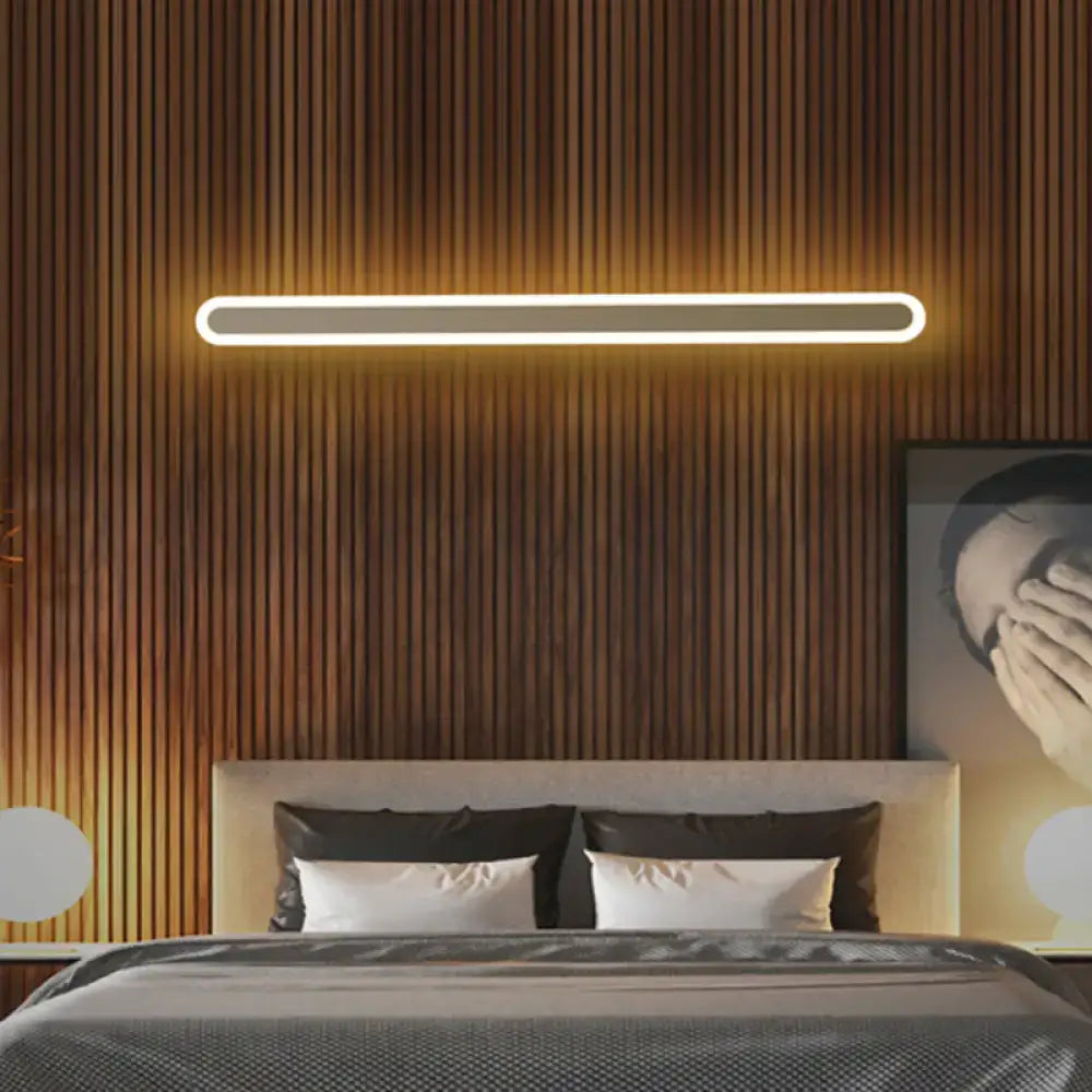 White acrylic wall sconce by Decorbites, rounded LED bar with warm glow on wood slat bedroom wall on Tampa Home & Garden Store