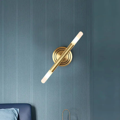 Brass slim tube wall sconce by Decorbites on blue wall with backplate and frosted LED ends on Tampa Home & Garden Store