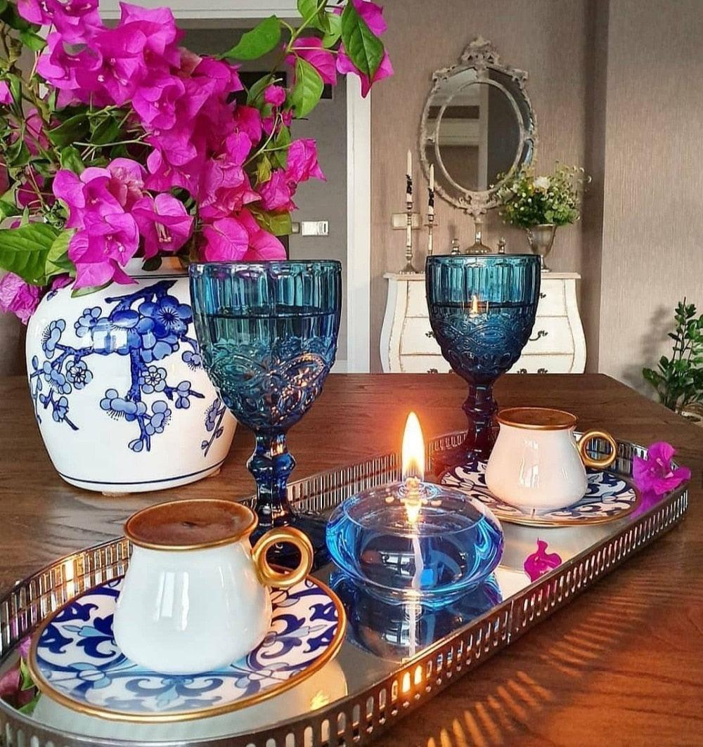 Stevvex blue glass oil candle on a mirrored tray with two goblet candles and white porcelain cups on Tampa Home & Garden Store