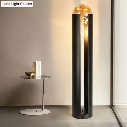Floor lamp with black pillars and glass globe beside a round table with white vase on Tampa Home & Garden Store