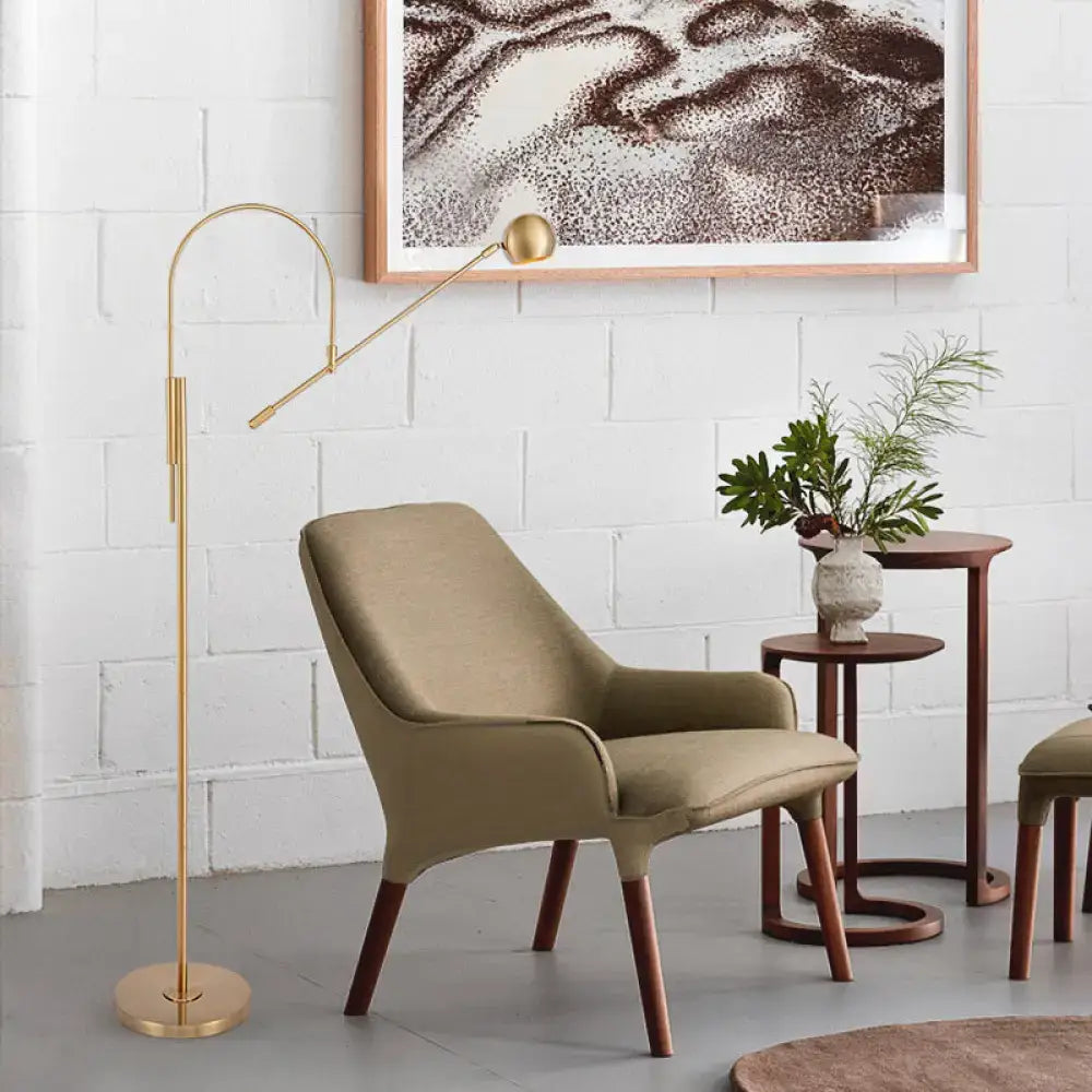 Olive upholstered armchair with tapered wooden legs; gold arc floor lamp and two nesting tables on Tampa Home & Garden Store