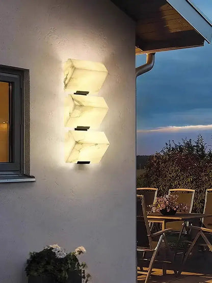 Modern onyx amber geometric LED outdoor wall sconce with 3 stacked blocks lighting the exterior wall on Tampa Home & Garden Store