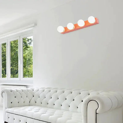 Modern orange-white 3-bulb vanity light by Decorbites mounted on wall above tufted sofa on Tampa Home & Garden Store