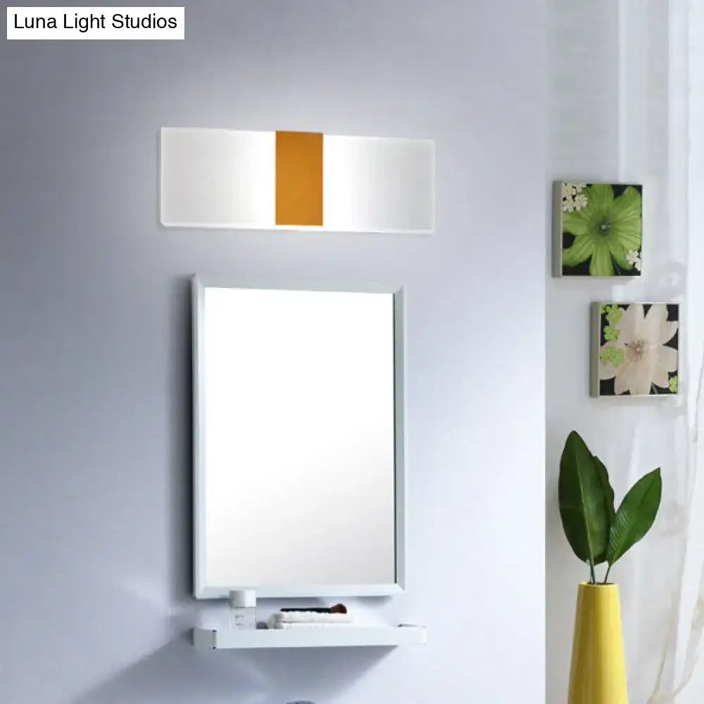 Metal oval LED sconce with white body and orange center panel above bathroom mirror on Tampa Home & Garden Store