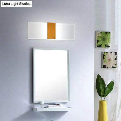 Metal oval LED sconce with white body and orange center panel above bathroom mirror on Tampa Home & Garden Store