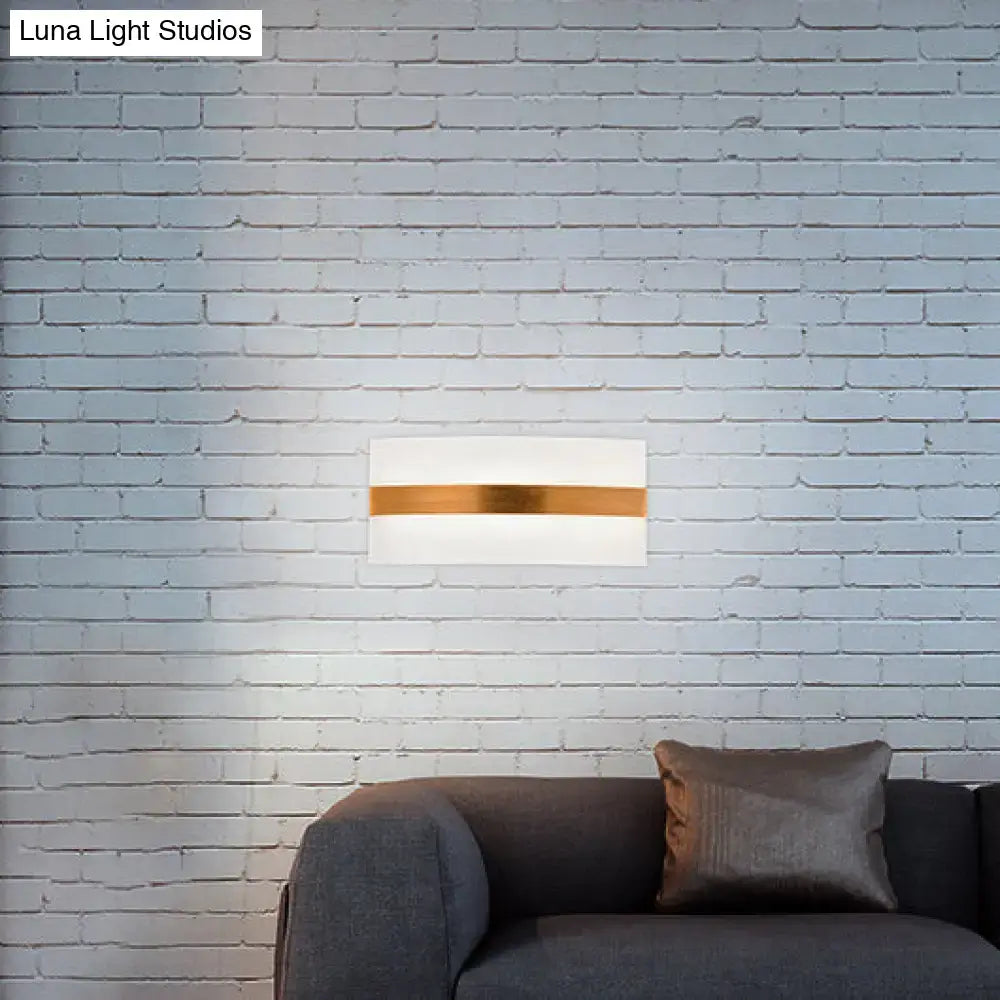 Decorbites metal oval LED sconce with white body and gold band, mounted on a light brick wall above a gray sofa on Tampa Home & Garden Store