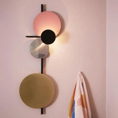 Pink gold circular wall light by Decorbites with layered metal discs on a slim black rod on Tampa Home & Garden Store