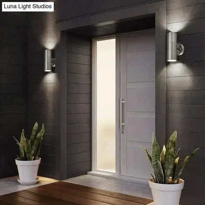Modern silver cylindrical outdoor wall sconces by Decorbites, paired beside entry door on Tampa Home & Garden Store