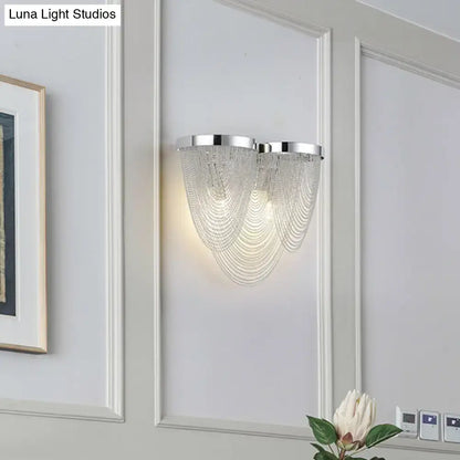 Silver tassel wall sconce by Decorbites with crystal bead strands on a gray paneled wall on Tampa Home & Garden Store