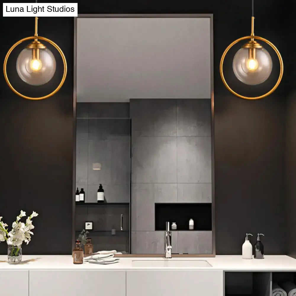 Pair of gray glass globe wall sconces with brass rings by Decorbites flanking a mirror on Tampa Home & Garden Store