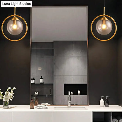 Pair of gray glass globe wall sconces with brass rings by Decorbites flanking a mirror on Tampa Home & Garden Store