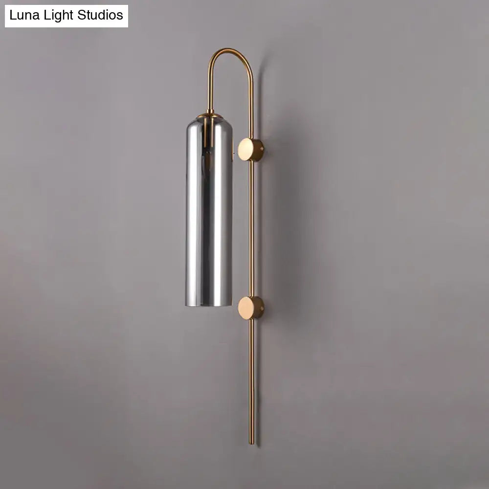 Decorbites gray glass cylindrical wall sconce with brass mounting and curved backplate on Tampa Home & Garden Store