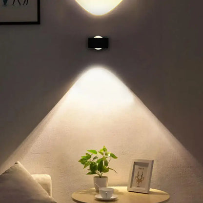 Black silver LED wall sconce by Decorbites mounted on white wall above a round table with plant on Tampa Home & Garden Store