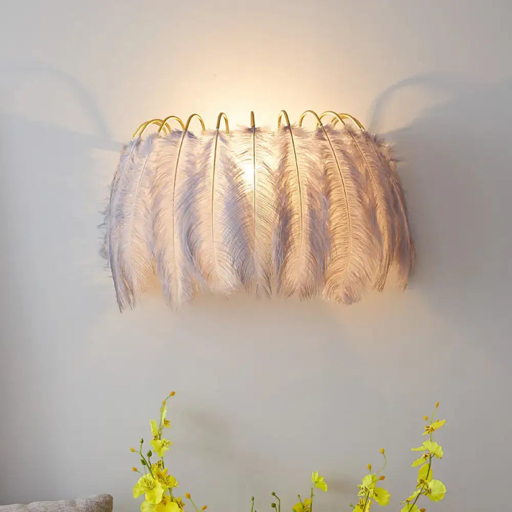 Grey feather parlor wall sconce with a gold wire frame and soft grey feathers, warm glow on Tampa Home & Garden Store