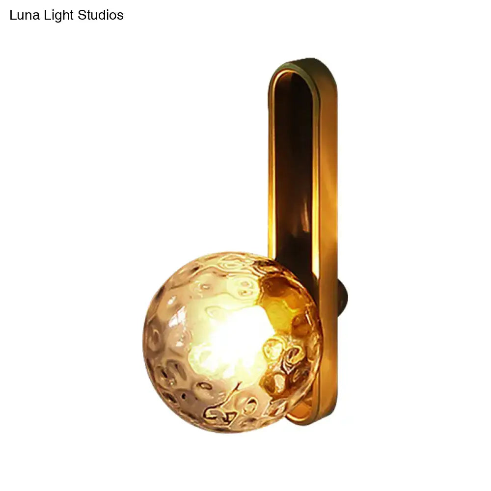 Gold-toned metal wall sconce with hammered glass globe light fixture on Tampa Home & Garden Store