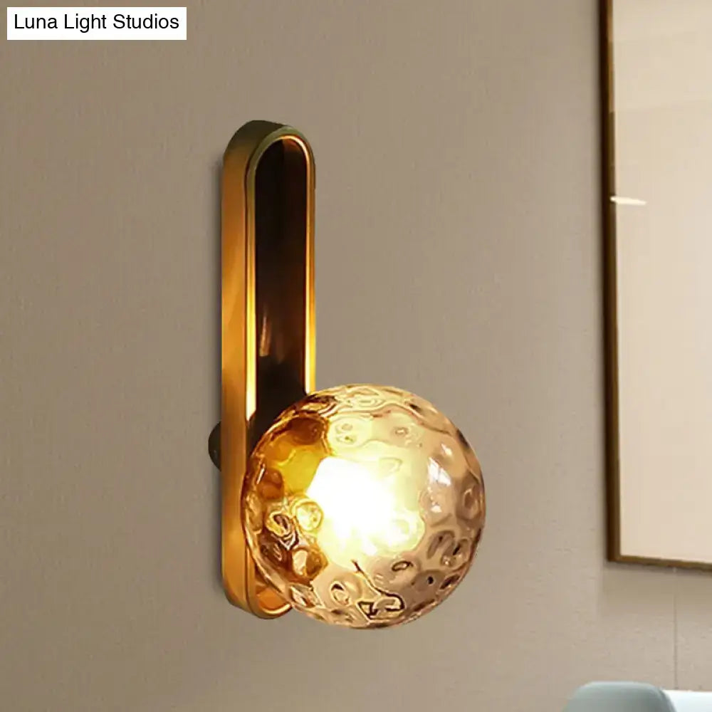 Brass wall sconce with textured amber glass globe on Tampa Home & Garden Store