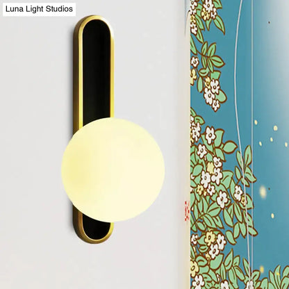 Wall sconce by Luna Light Studios with black backplate and frosted globe against florals on Tampa Home & Garden Store