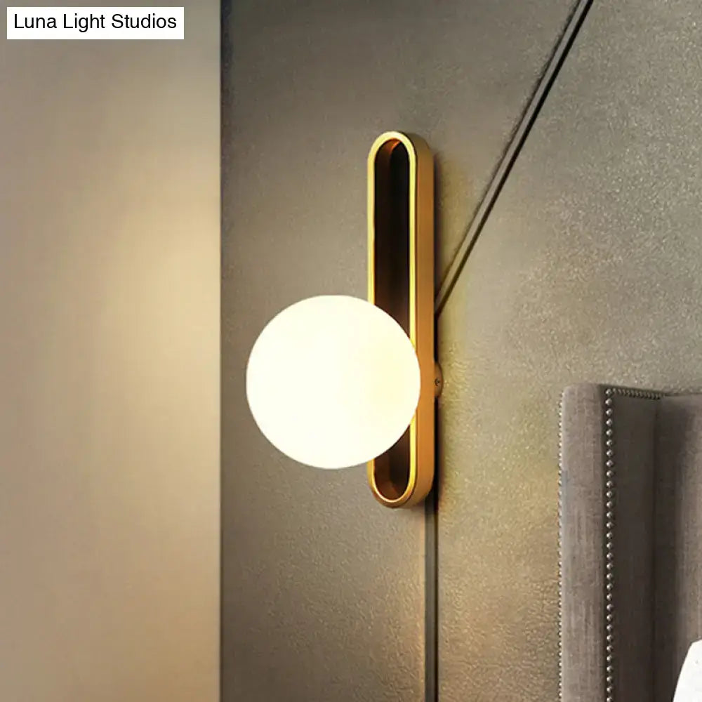Gold wall sconce with vertical oval backplate and frosted white glass globe on Tampa Home & Garden Store