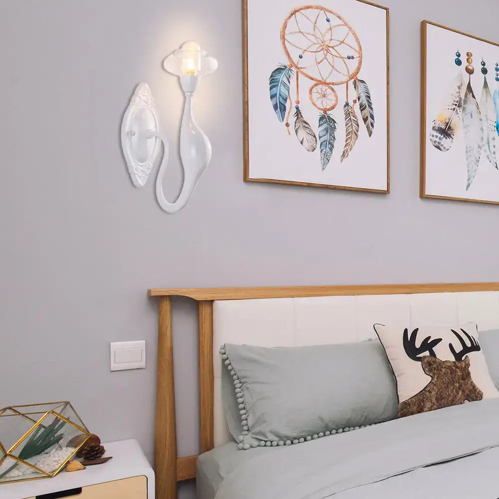 White ceramic wall sconce with curved arm and cloud shade beside framed art on gray wall on Tampa Home & Garden Store