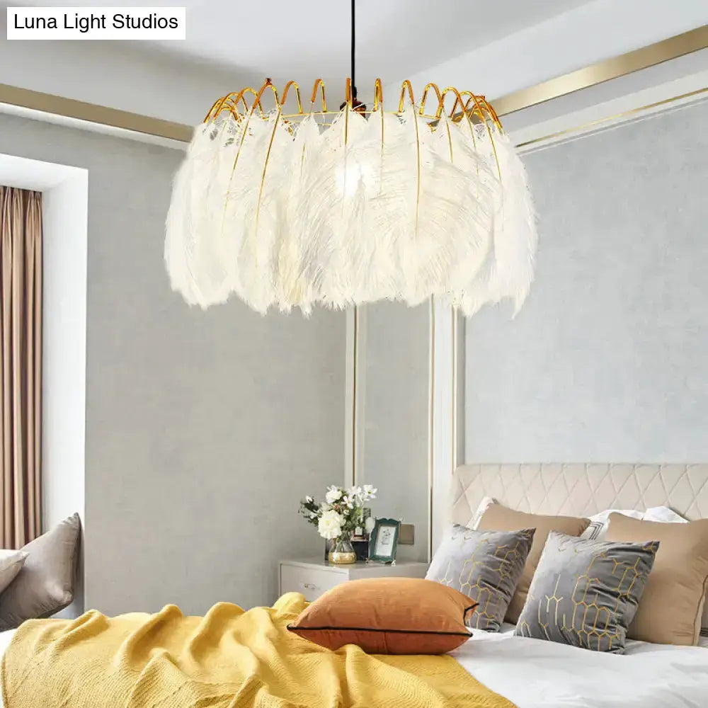 Modern white feather chandelier with gold wire pendant light over a bed in a bedroom on Tampa Home & Garden Store