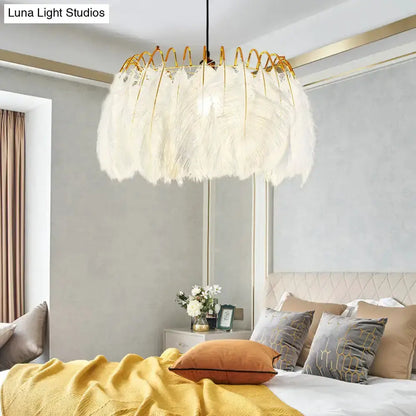 Modern white feather chandelier with gold wire pendant light over a bed in a bedroom on Tampa Home & Garden Store