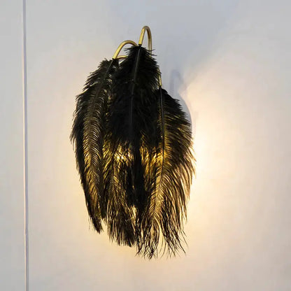 Modern feather metal wall sconce with black plume and gold arc frame emits warm light on Tampa Home & Garden Store