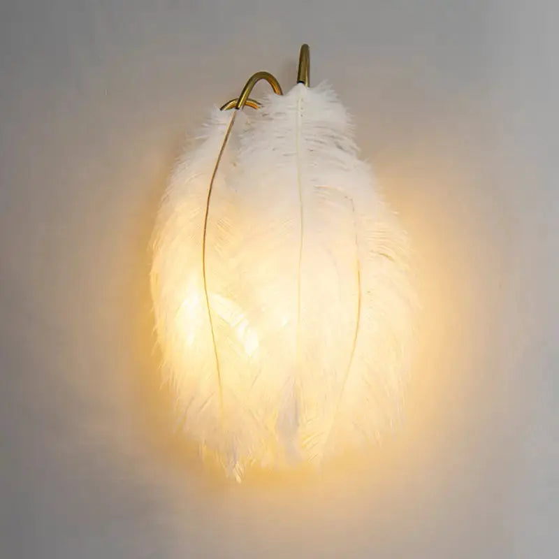 White feather metal wall sconce with brass arch frame, Decorbites bedroom lighting, warm glow on Tampa Home & Garden Store