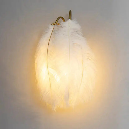 White feather metal wall sconce with brass arch frame, Decorbites bedroom lighting, warm glow on Tampa Home & Garden Store