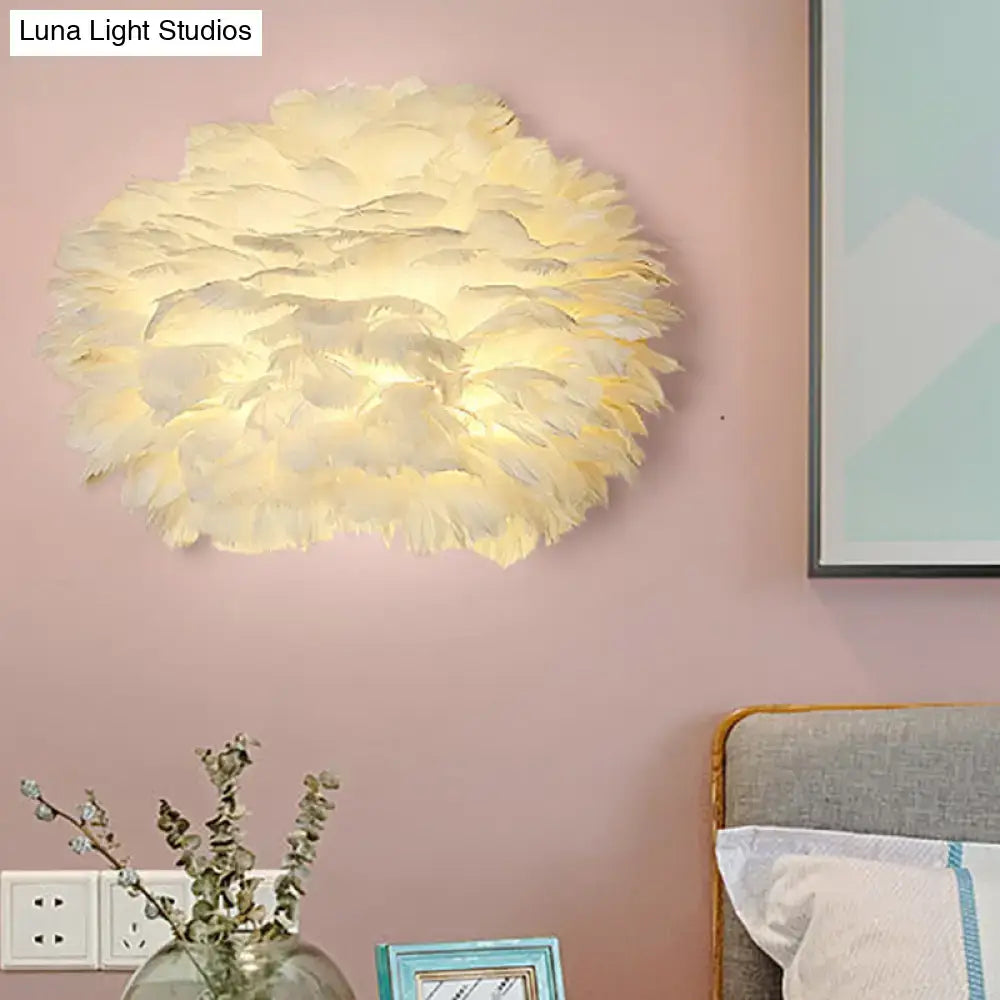 White Feather Wall Lamp with round fluffy feather shade adds soft glow to pink wall beside the bed on Tampa Home & Garden Store