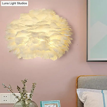 White Feather Wall Lamp with round fluffy feather shade adds soft glow to pink wall beside the bed on Tampa Home & Garden Store