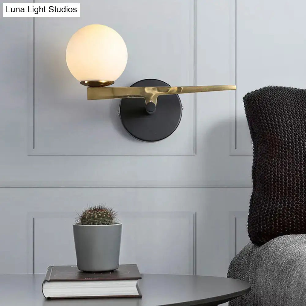Gold glass sphere wall light with brass arm by Decorbites on black wall mount on Tampa Home & Garden Store